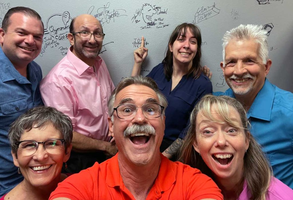 All members of the Improv Colorado Troupe, looking at the camera with big smiles